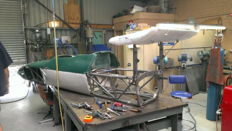 Rear wing getting fitted. Side panels are also fitted and cover the new aluminium fuel tanks.